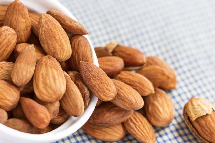 Roasted almonds, salt in bowl of white on the tablecloth. Almonds are rich in nutrients, vitamins, and minerals that are essential to the body.