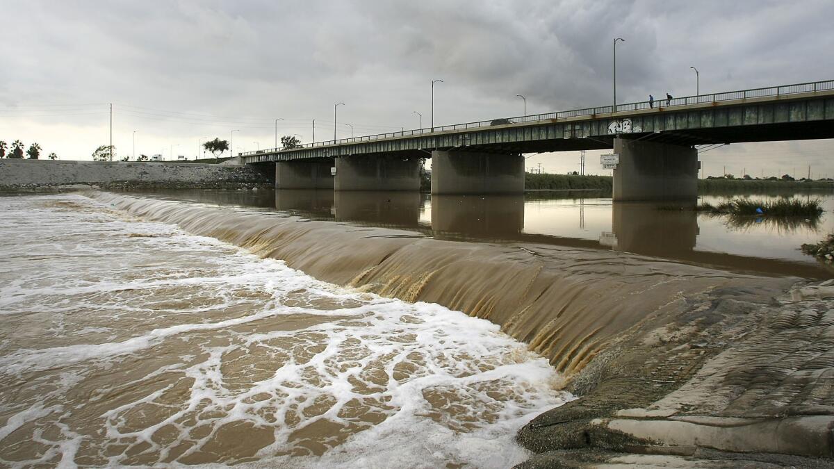 A stormwater-swollen Los Angeles River flows under the Anaheim Street bridge in Long Beach on its way to the Pacific Ocean.