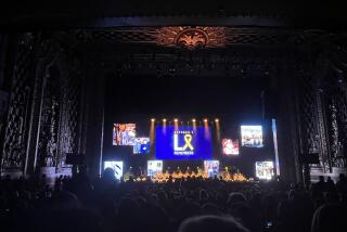 Inside a darkened theater, an audience watches the stage.