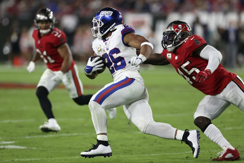 New York Giants running back Saquon Barkley (26) runs away from Tampa Bay Buccaneers inside linebacker Devin White (45) during the first half of an NFL football game Monday, Nov. 22, 2021, in Tampa, Fla. (AP Photo/Mark LoMoglio)
