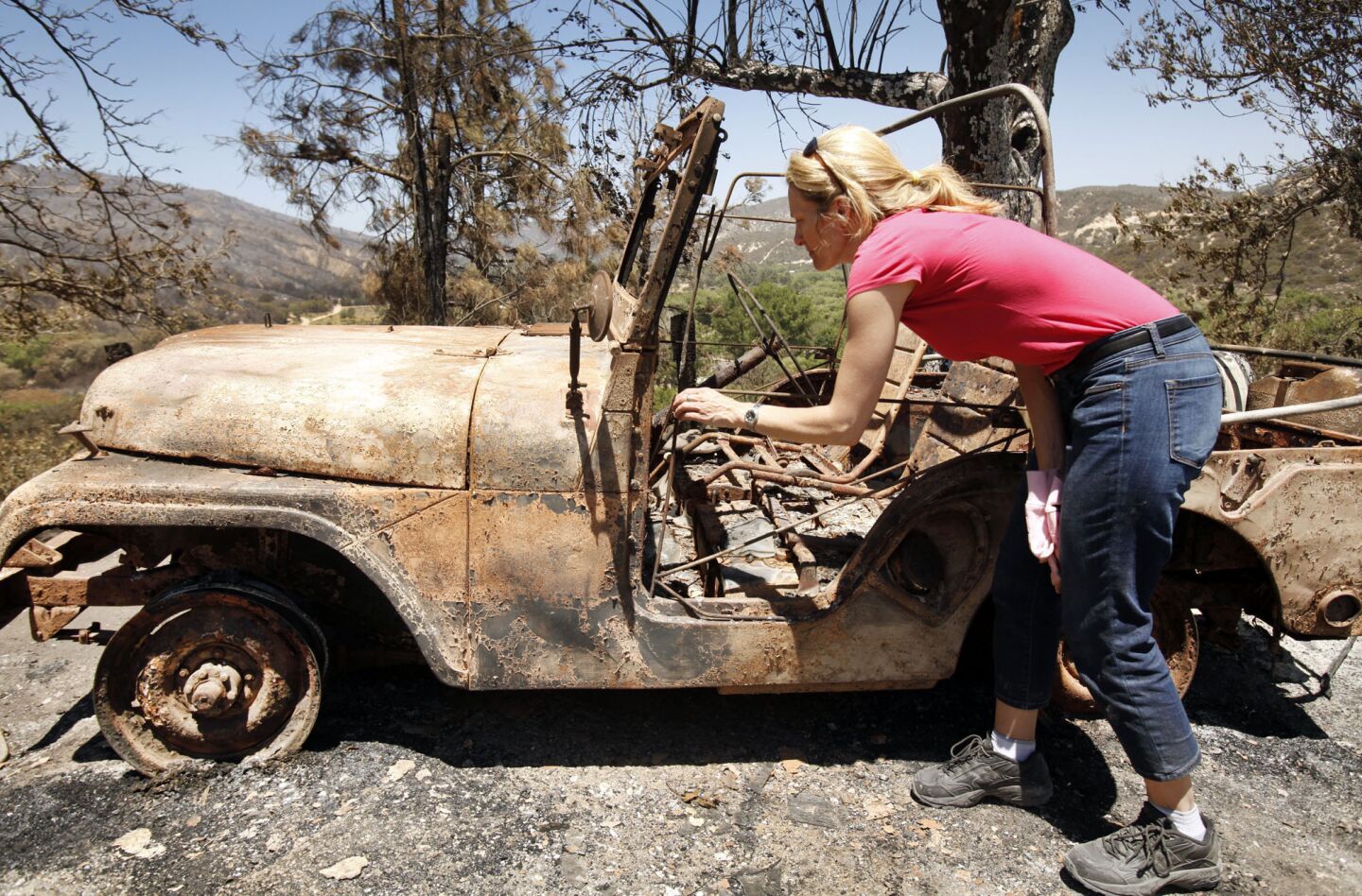 Holly Solberg looks at the charred remains of her father's recently restored 1952 Willys Jeep.