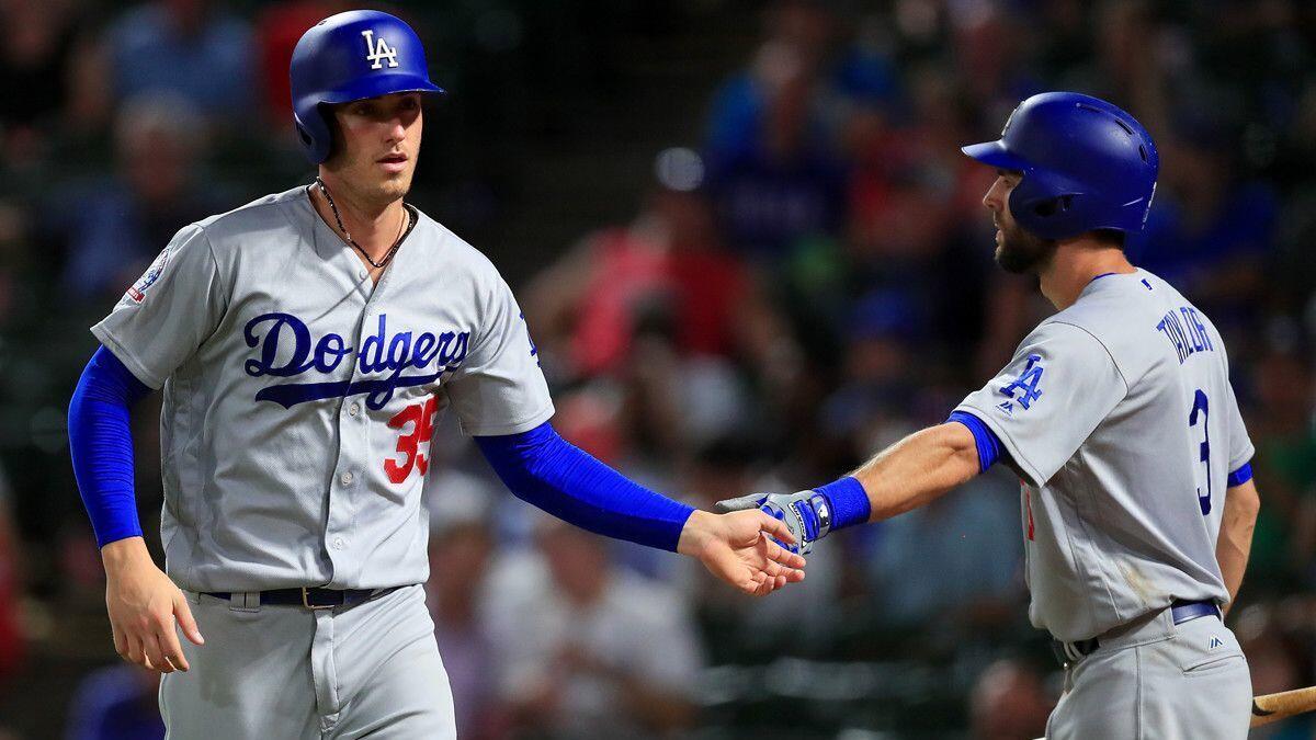 Dodgers' Cody Bellinger, left, celebrates with Chris Taylor after scoring against the Texas Rangers on Tuesday.