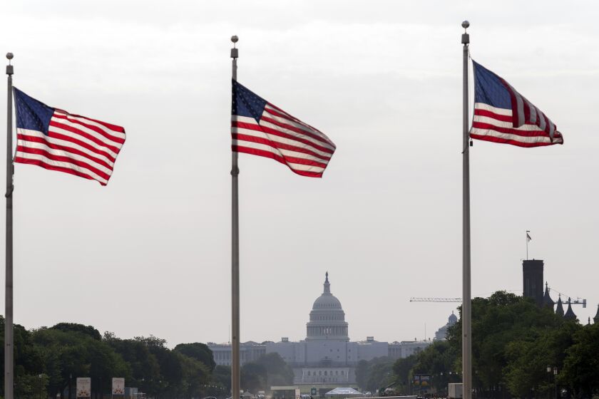 American flags fly with a cloudy sky above the U.S. Capitol in Washington, Friday, June 9, 2023. While the air quality remains unhealthy, the record smoke pollution from wildfires in eastern Canada this week has diminished significantly over the nation's capital. (AP Photo/Jose Luis Magana)