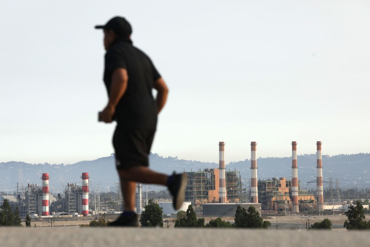 A person jogs, with the steam stacks of the L.A. Department of Water and Power Valley Generating Station in the background