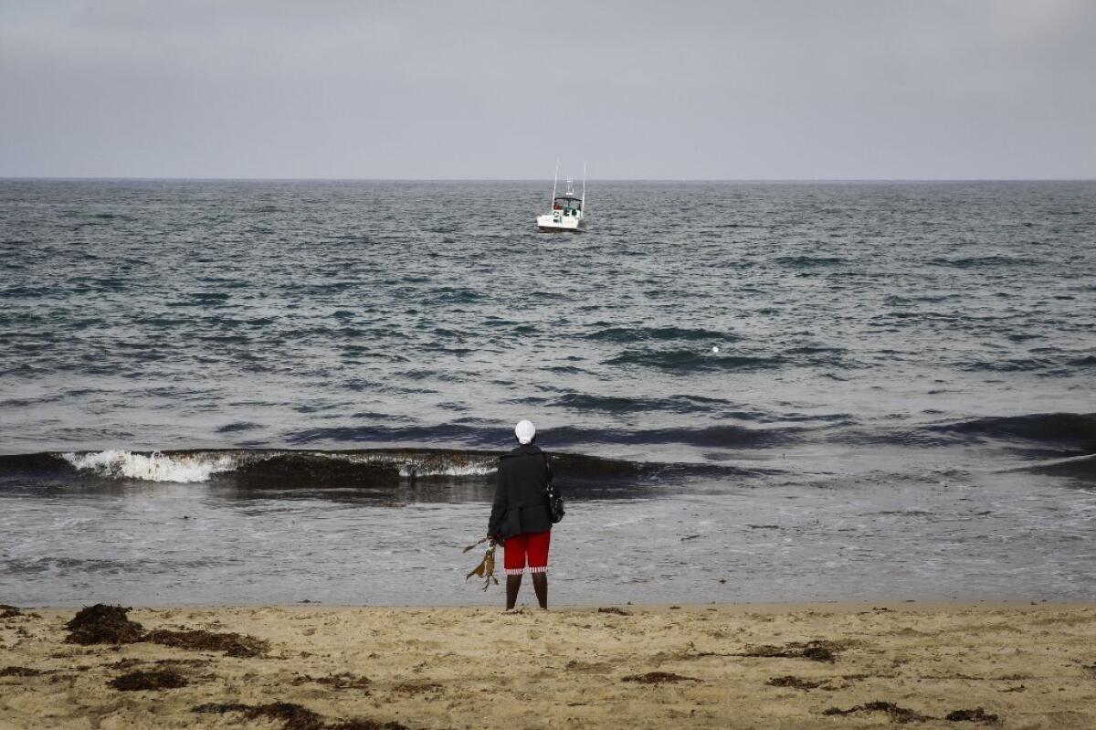Louise Bernardez, grandmother of missing swimmer Marlon Fajardo, 21, looks out at the ocean as lifeguards search for the man near Redondo Beach. Divers later recovered a body.