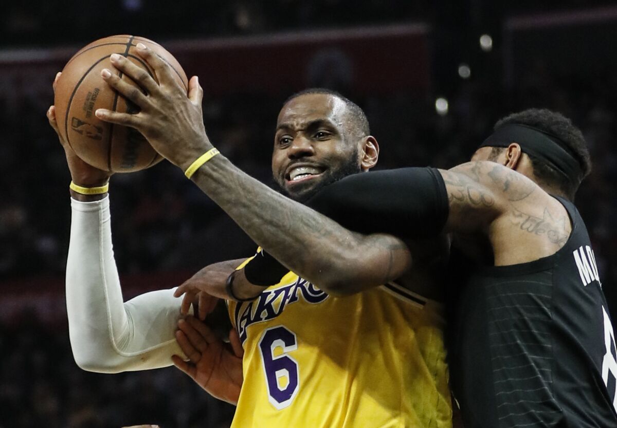 Lakers forward LeBron James is fouled by Clippers forward Marcus Morris Sr. while trying to power his way to the basket.