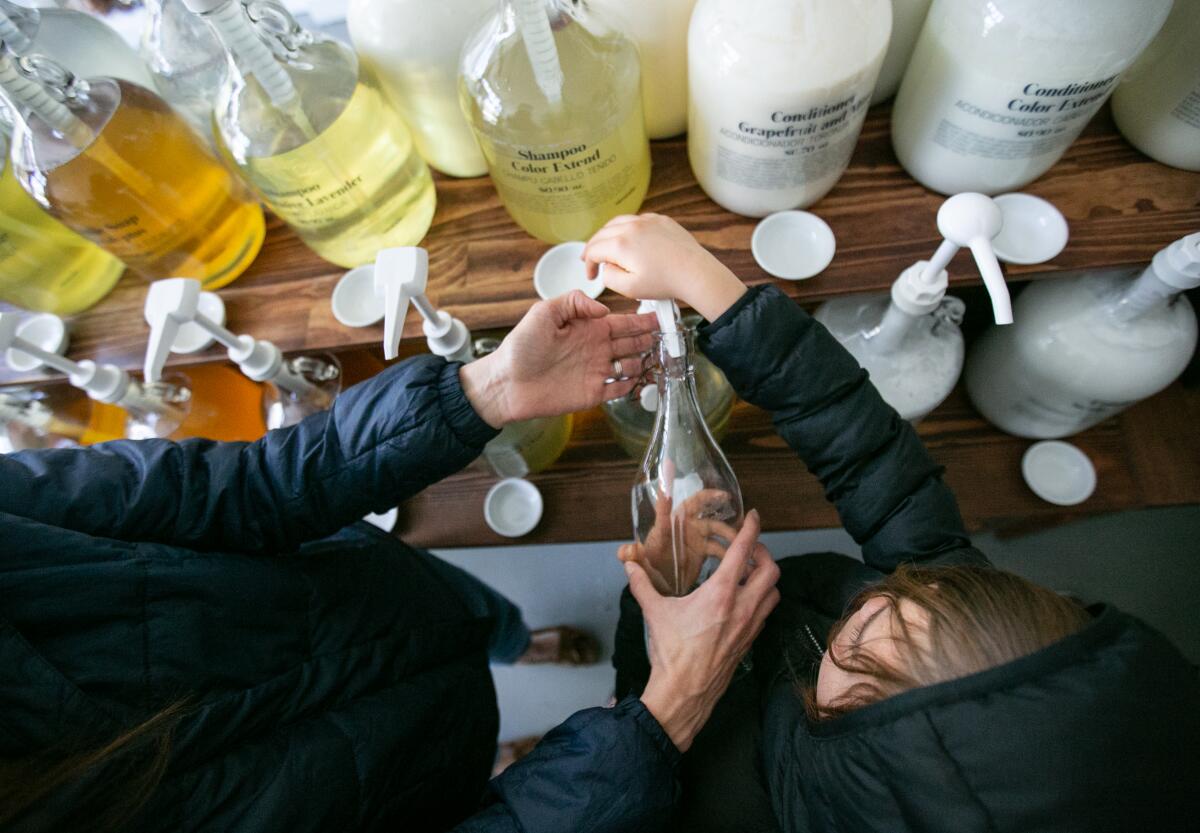 Kim Staley of Pasadena helps her children fill a bottle with hand soap at Sustain.LA, a zero-waste store with a refill station.