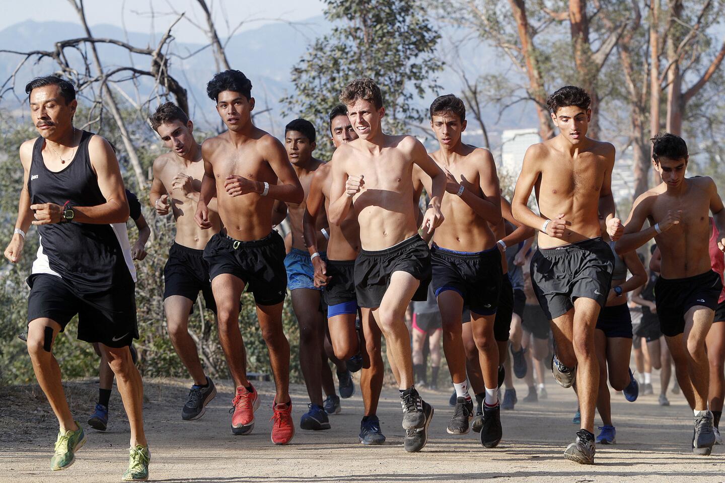 Runners climb the initial hill about a quarter mile from the starting line in a 5k trail race by Burbank High School at Griffith Park in Los Angeles on Tuesday, July 31, 2018.