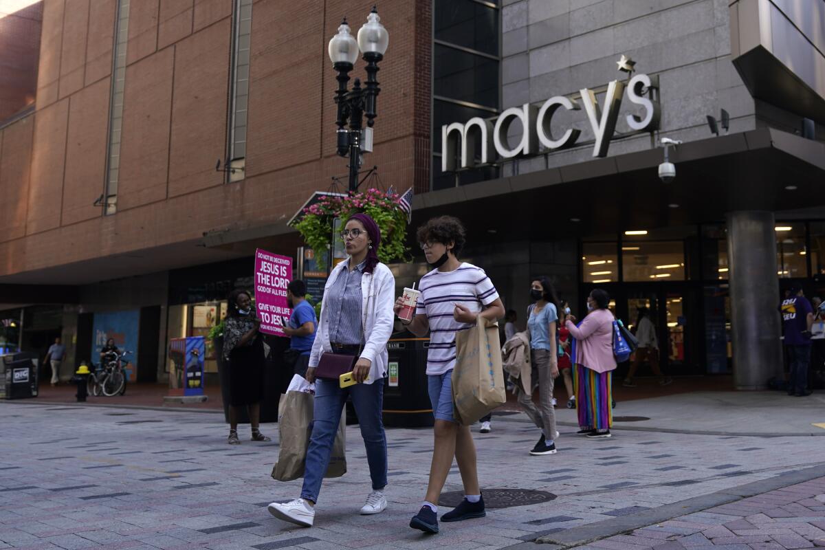 People leave a Macy's with shopping bags.