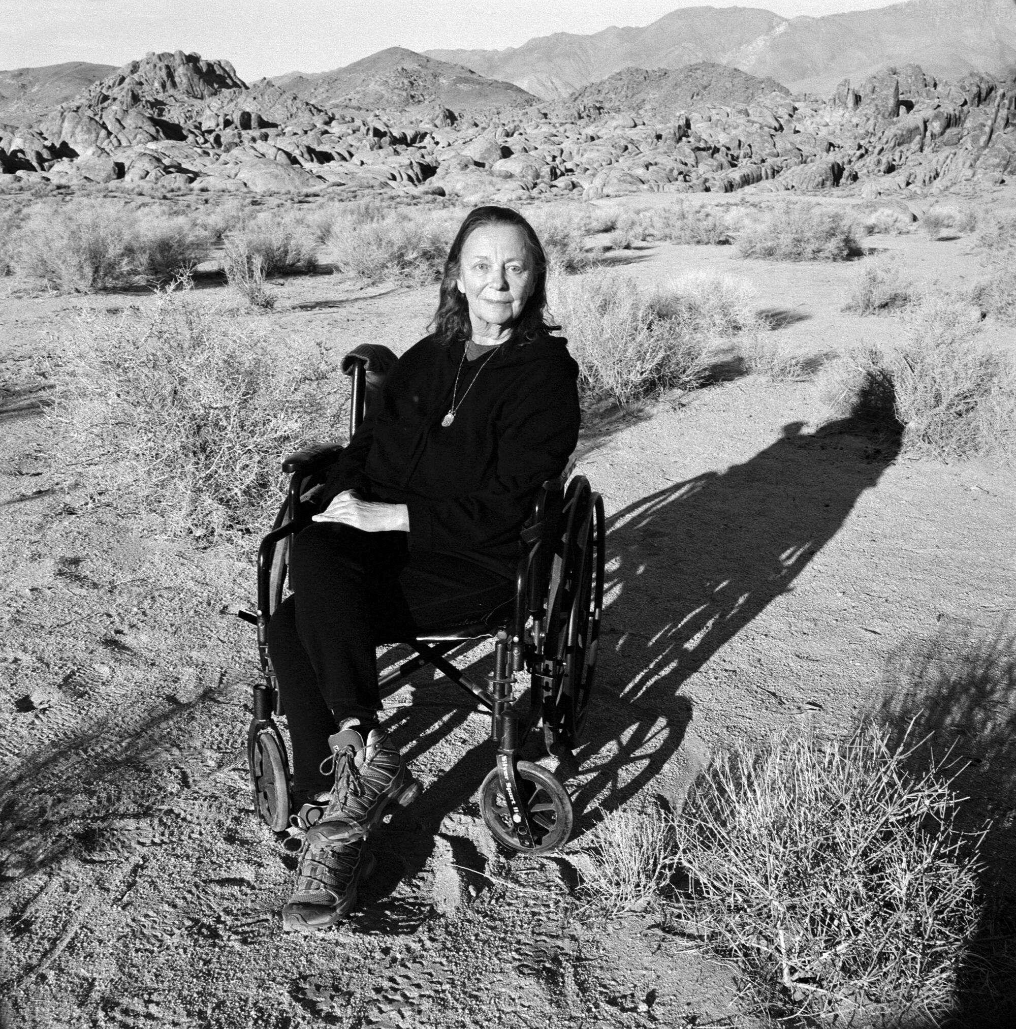 Marianne Wiggins sits in a hilly, desert landscape.