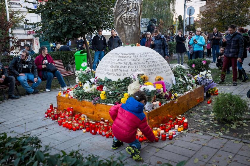 A child lights a candle in front of a monument erected in the memory of the 64 people who were killed when Colectiv club caught fire during a rock concert in October 2015 in Bucharest, Romania.