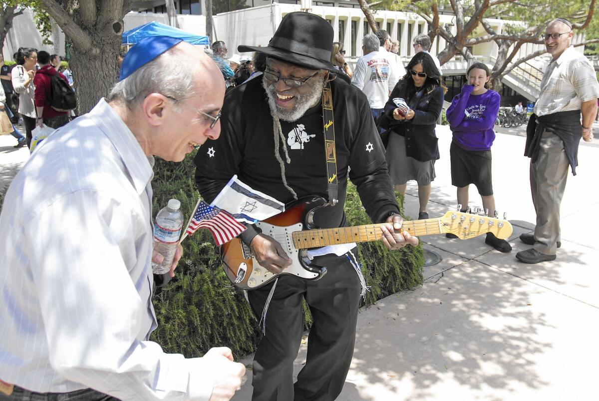 Rabbi Blue, center, plays guitar and dances with a supporter during Thursday's pro-Israel rally at the UC Irvine campus.