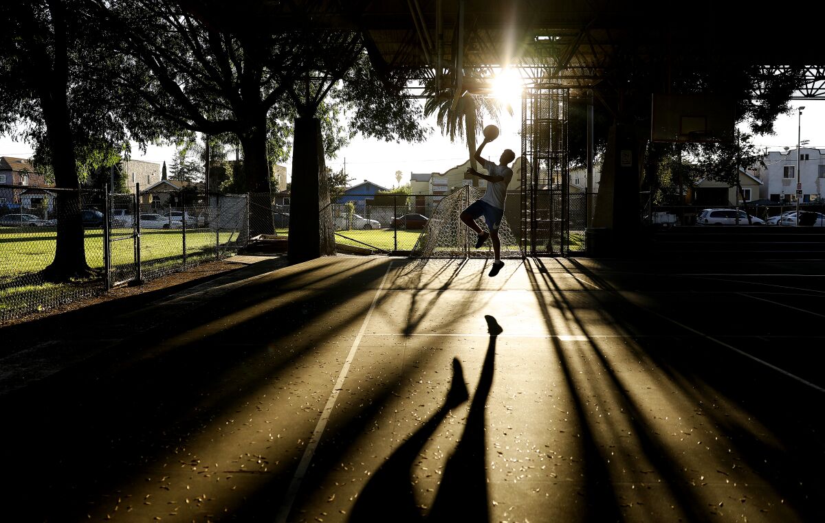 Keven Lopez, 16, plays basketball solo at a court near South Pecan Street in Boyle Heights.