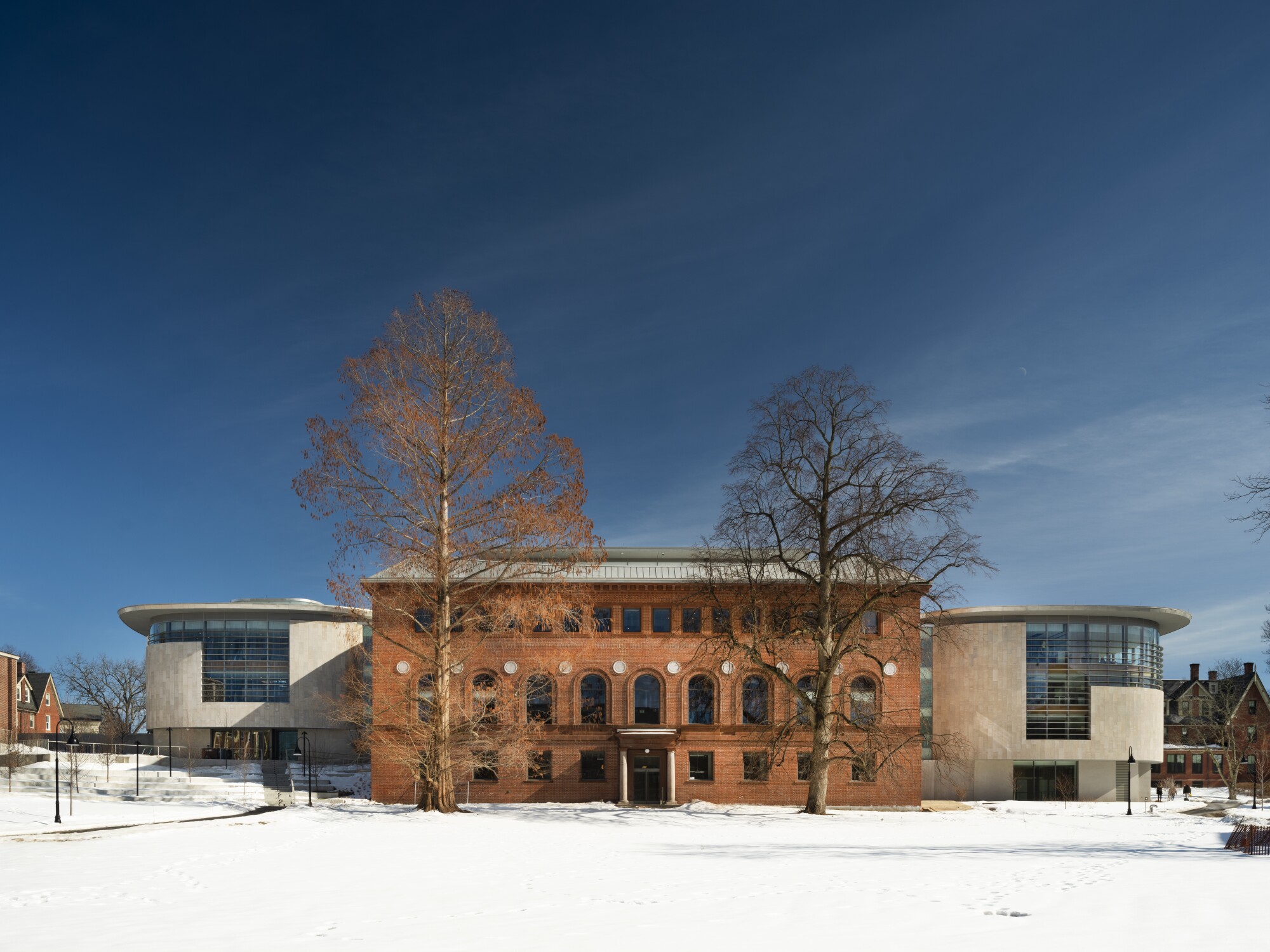 A wide view of Neilson Library on a snowy day shows off the two new wings covered in pale limestone.