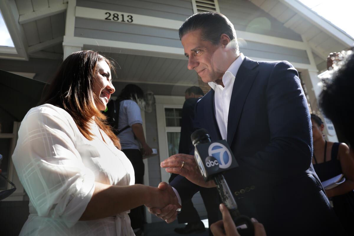 Superintendent Alberto Carvalho, right, shakes hands with a woman outside a home