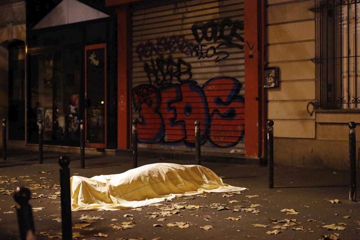FILE - In this Friday Nov. 13, 2015 file photo, a victim under a blanket lays dead outside the Bataclan theater in Paris. France is putting on trial 20 men accused in the Nov. 13, 2015, Islamic State terror attacks on Paris that left 130 people dead and hundreds injured. Nine gunmen and suicide bombers struck within minutes of each other at the national soccer stadium, the Bataclan concert hall and restaurants and cafes. Salah Abdeslam, the lone survivor of the terror cell from that night is among those being tried for the deadliest attack in France since World War II. (AP Photo/Jerome Delay, File)