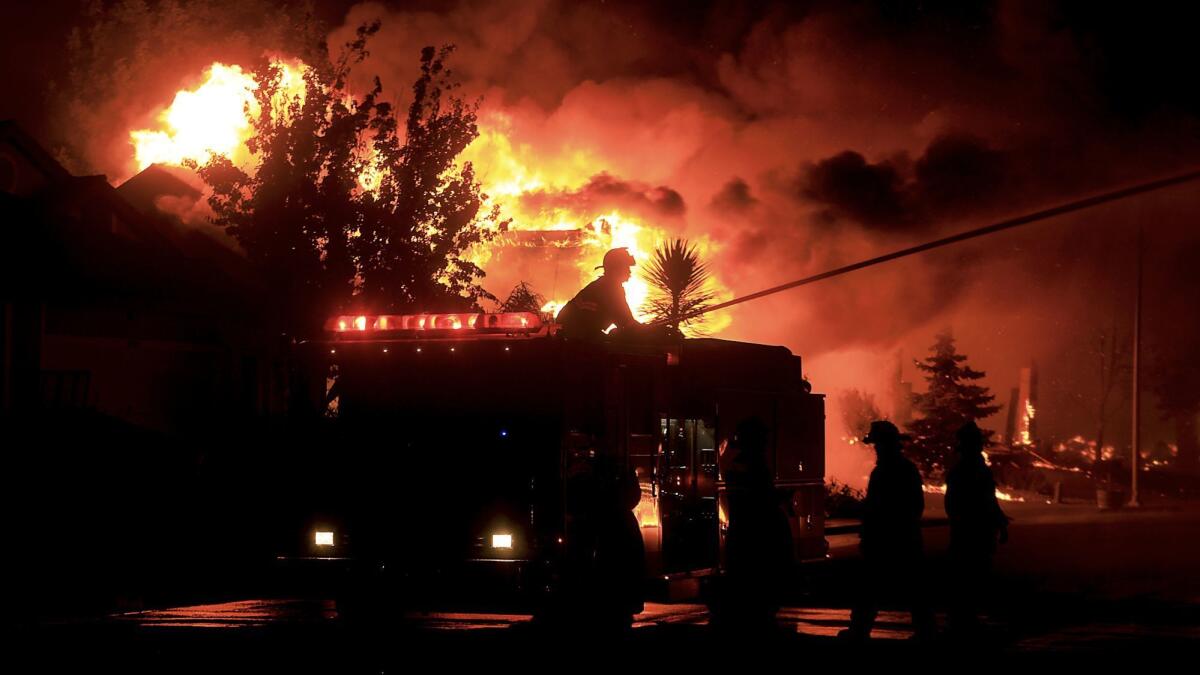 Firefighters shoot a stream of water at structures under threat in the Coffey Park neighborhood of Santa Rosa.