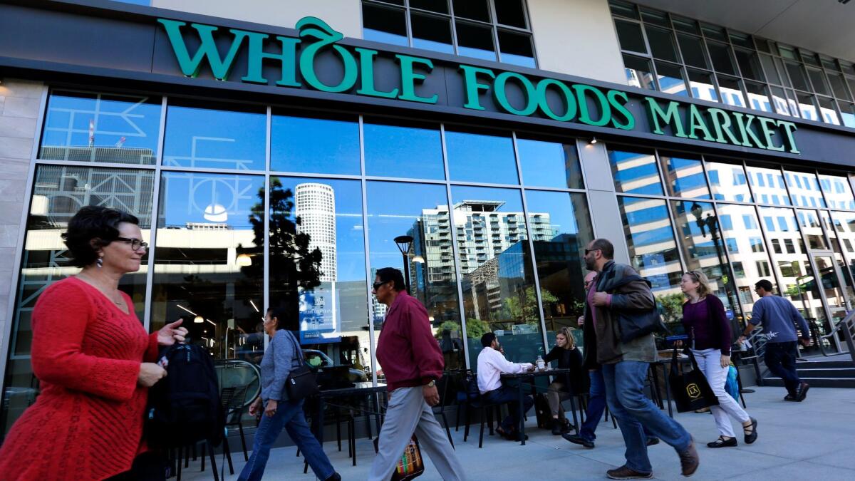 Pedestrians pass a Whole Foods Market in downtown Los Angeles in 2015. A recent report in the Financial Times said Albertsons owner Cerberus Capital Management was considering a takeover of the grocery chain.