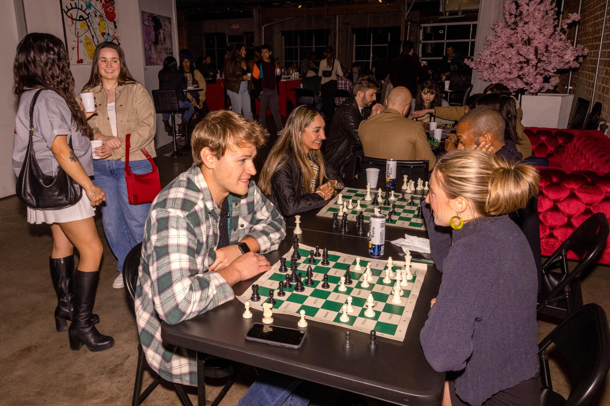 People sitting at tables socializing and playing chess.
