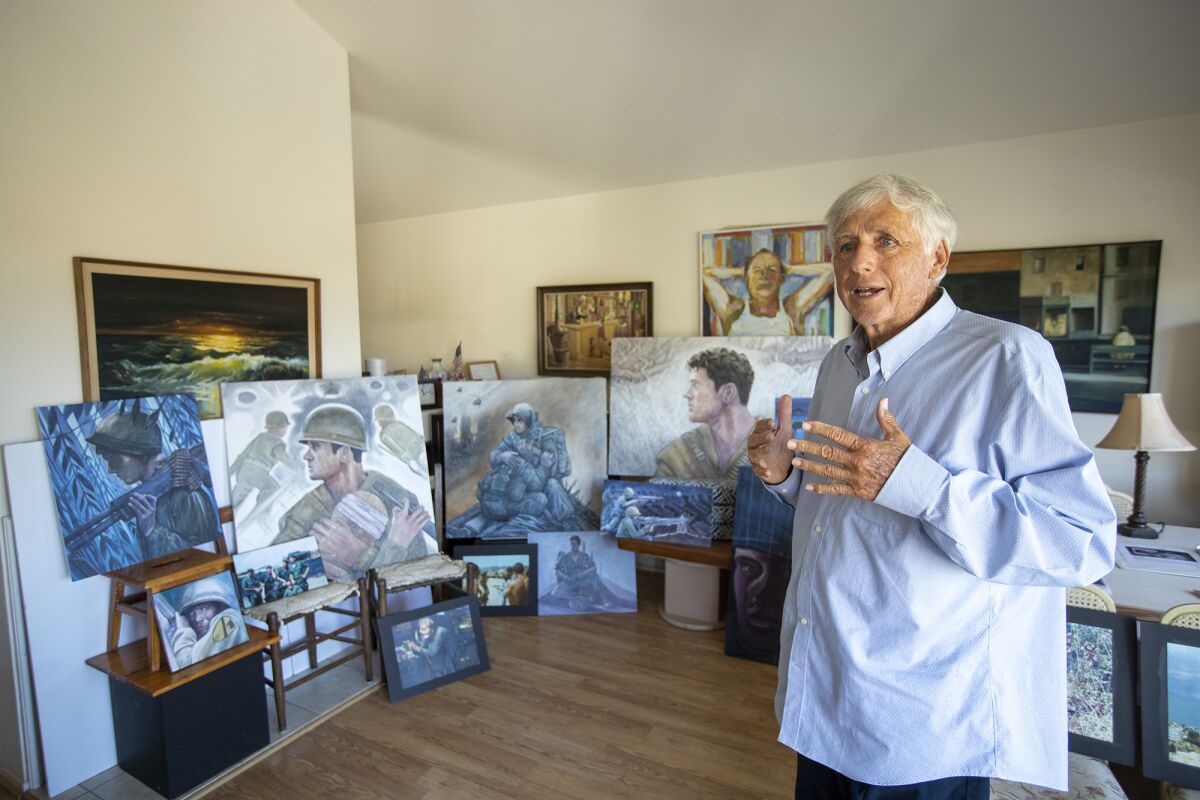 Ed Bowen stands amid a display of paintings at his home.