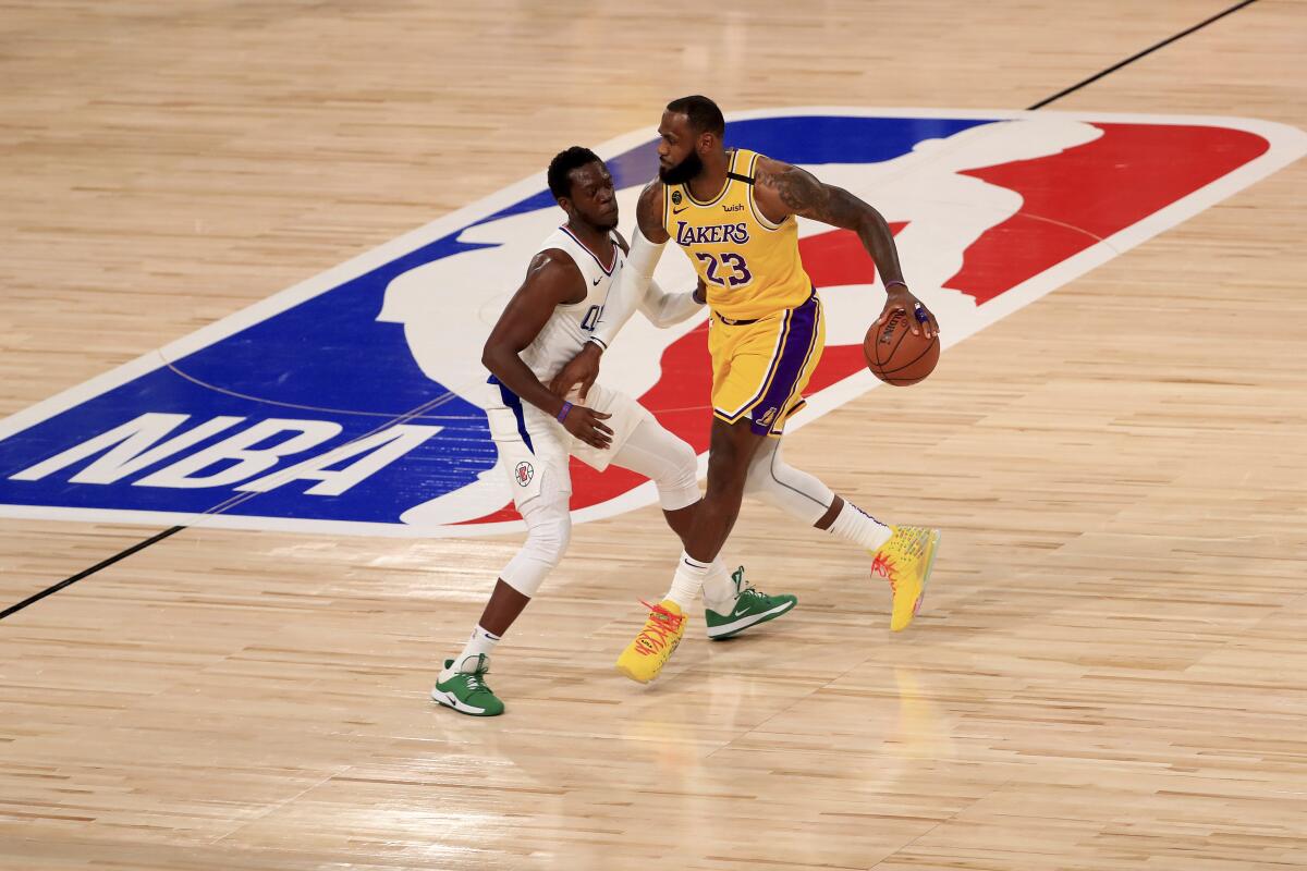 Lakers star LeBron James brings the ball up court against Clippers guard Reggie Jackson during the NBA's restart on July 30.