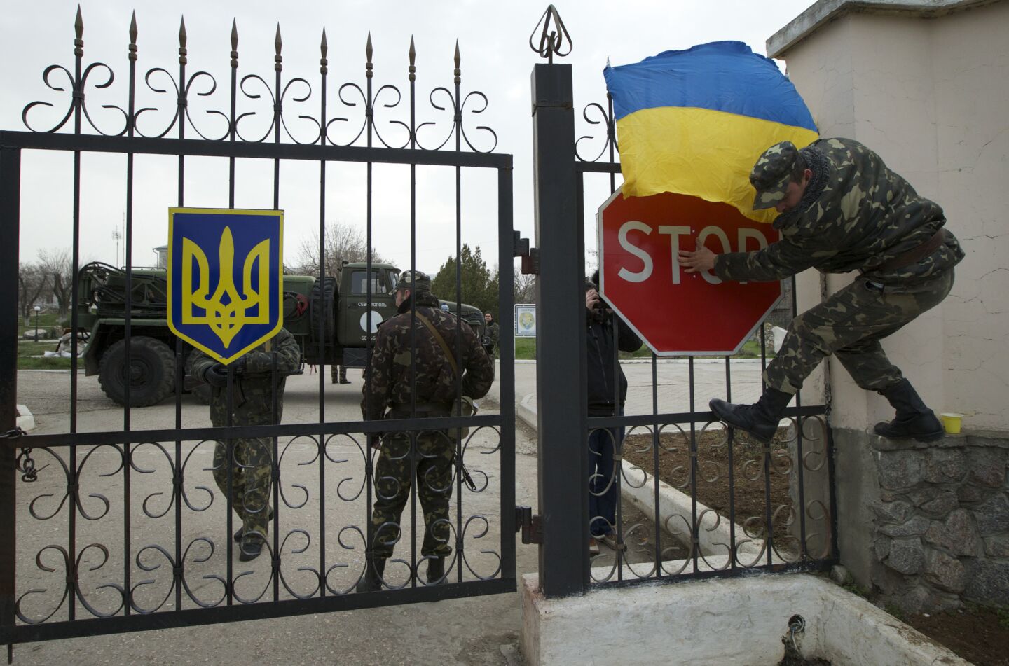 A Ukrainian airman puts the national flag over the gate as they guard what's left under their control at the Belbek air base, outside Sevastopol, Ukraine.