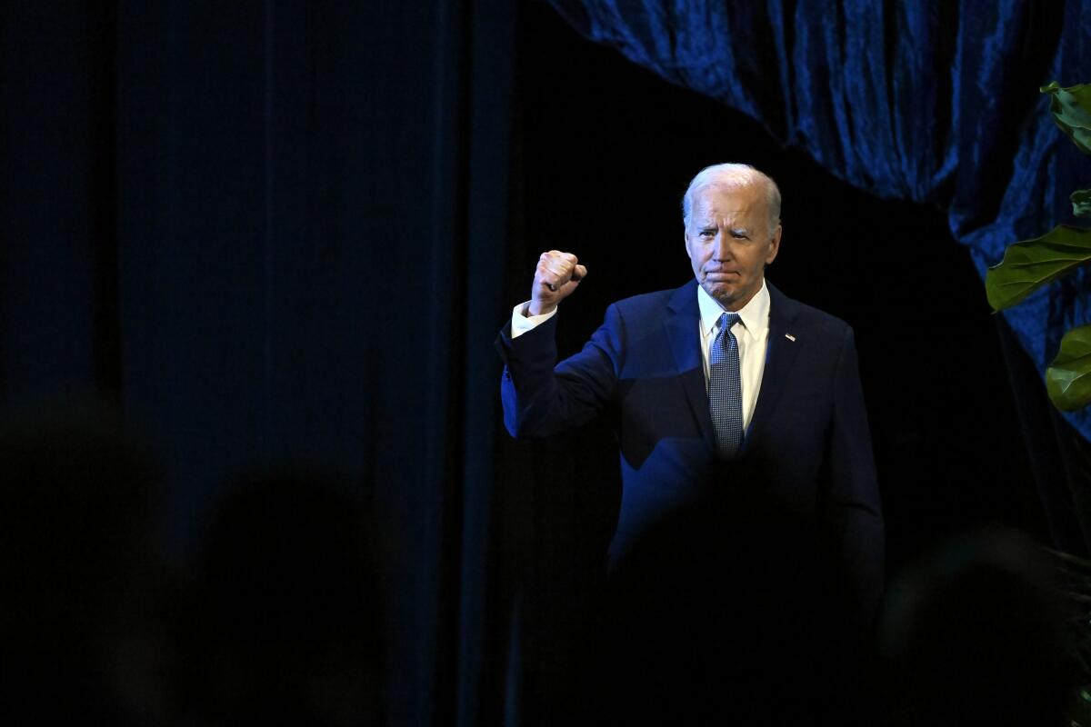 President Joe Biden walks on stage with his fist raised.