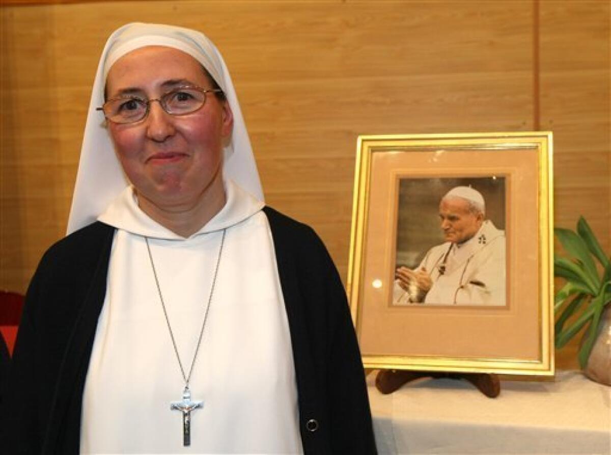 Sister Marie Simon-Pierre, stands next to a portrait of Pope John Paul II, during a press conference at Aix-en-Provence's archbishopric, Monday, Jan. 17, 2011. The pope has approved a miracle attributed to Pope John Paul II's intercession and set May 1 as the date for the beloved pontiff to be beatified. Pope Benedict XVI declared in a decree Friday, Jan. 14, 2011, that the cure of a French nun, sister Marie Simon-Pierre, who suffered from Parkinson's disease was miraculous, the last step needed for the beatification, in Monday, Jan. 17, 2011. (AP Photo/Claude Paris)