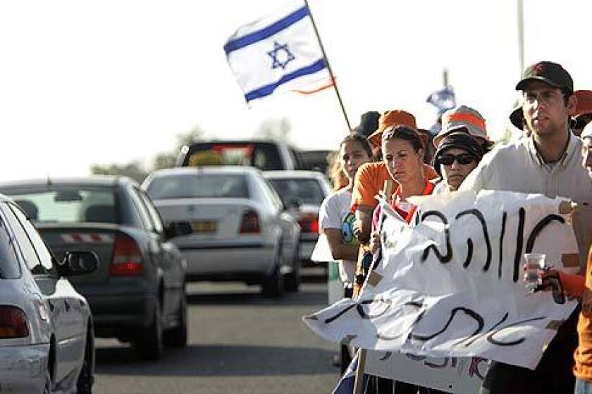 Supporters of Gush Katif settlers line the highway leading out of the Gaza Strip settlements Wednesday, holding signs and waving flags for the long line of settlers streaming out on the first day of forced evacuations.