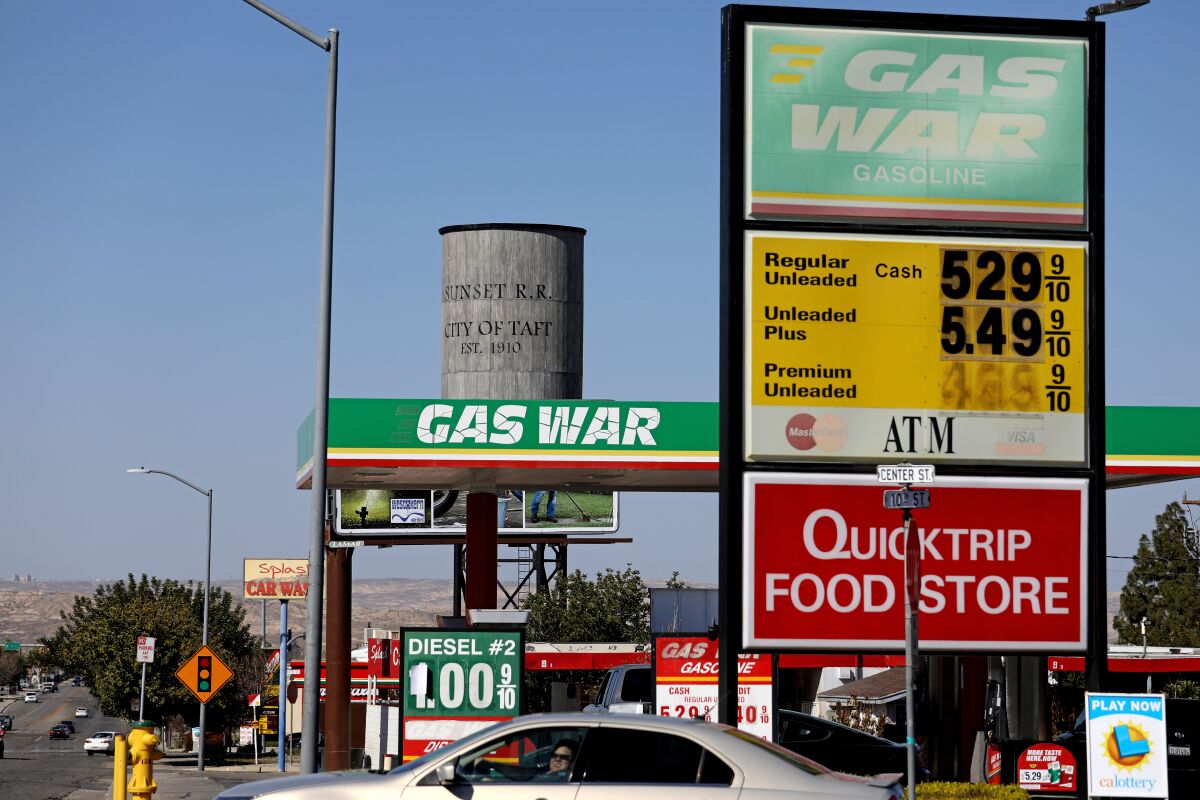 A water tower next to a "Gas War" station listing a gallon of regular at $5.29