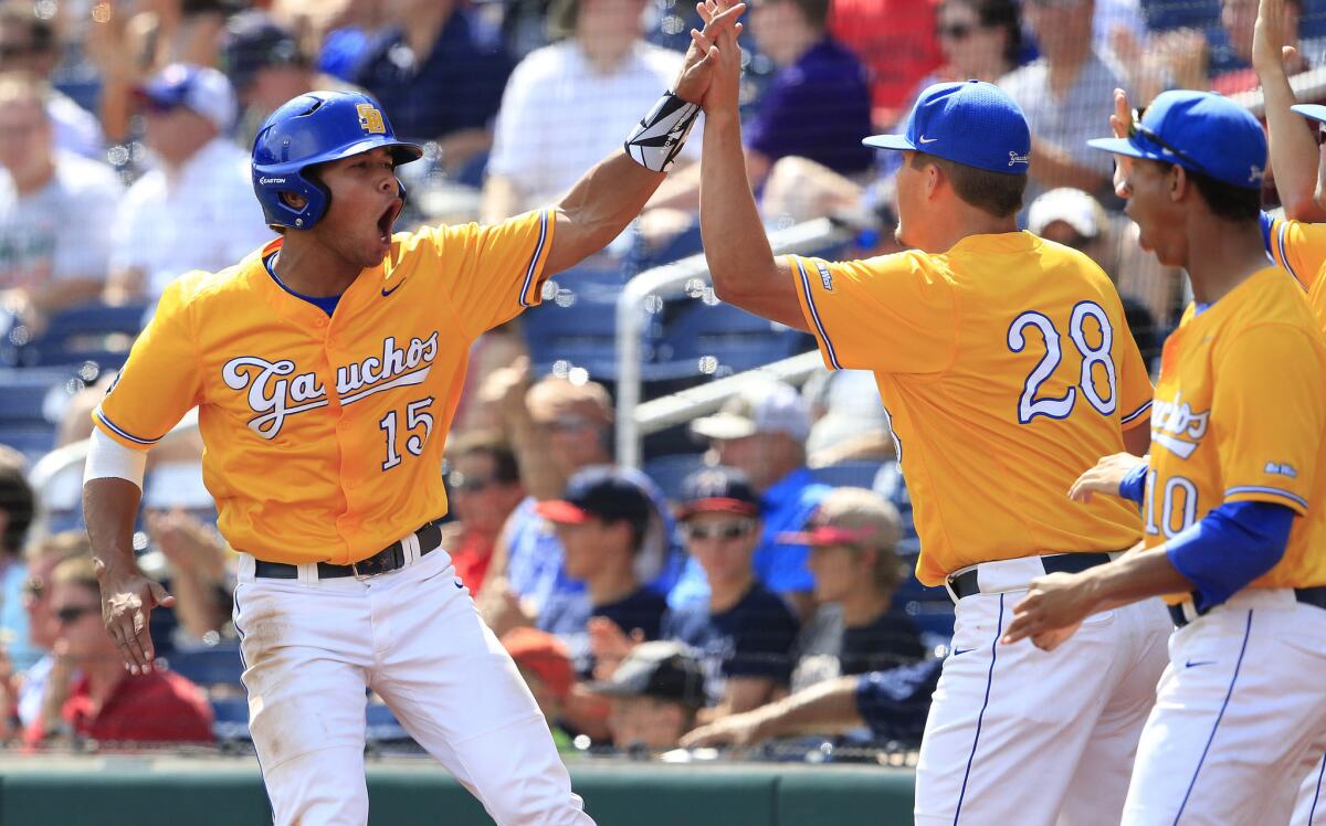 UC Santa Barbara outfielder Devon Gradford (15) celebrates with Joe Record (28) after scoring during the sixth inning of a College World Series elimination game against Miami.