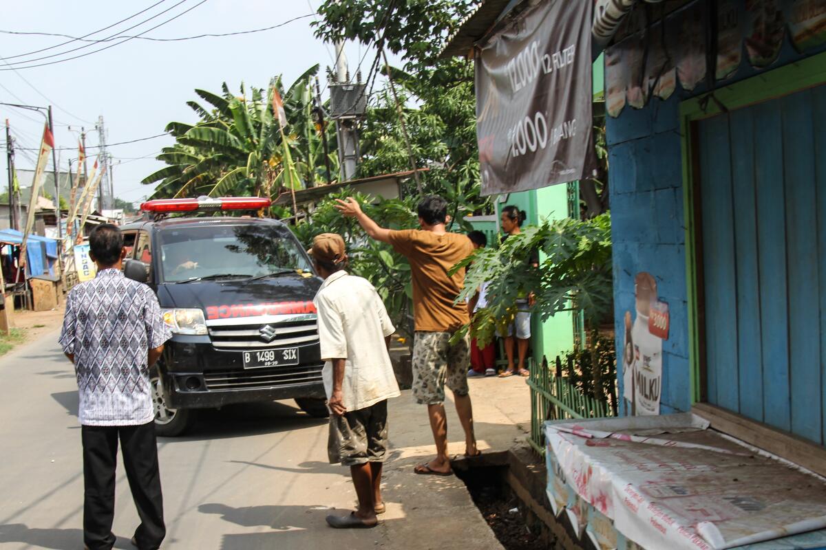 Three people gather in front of an ambulance. 