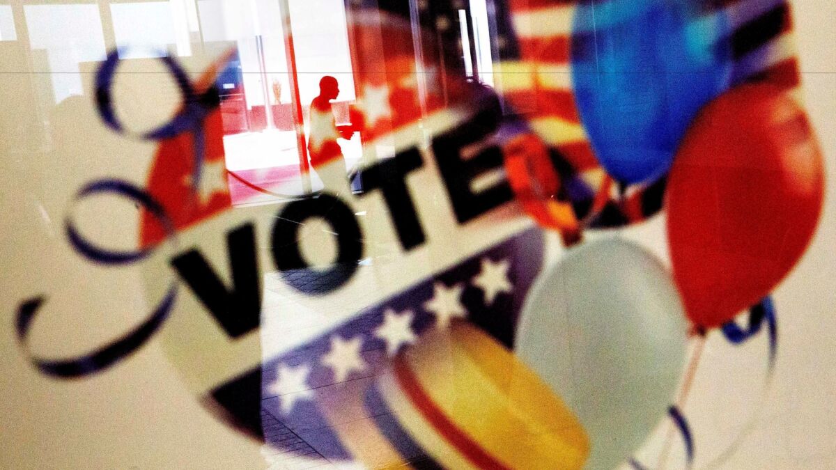 A voter is reflected in the glass frame of a poster while leaving an early voting polling site in Atlanta on Nov. 1.