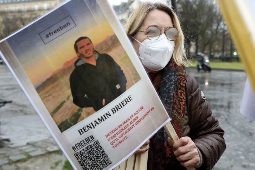 ARCHIVO - Una mujer sostiene una foto de Benjamin Briere durante un acto en París, Francia, 8 de enero de 2022. El francés fue condenado en Irán el martes 25 de enero de 2022 a 8 años de prisión por espionaje y propaganda, cargos que él rechaza. (AP Foto/Adrienne Surprenant, File)