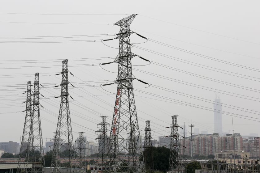 FILE - Power grid stand against the residential and office buildings in Beijing as the capital of China is shrouded by mild pollution haze on Monday, June 5, 2017. The International Energy Agency predicts Asia will consume half of the world's electricity by 2025. A new report by the Paris-based body forecasts that China alone will see its share of global electricity consumption grow from a quarter in 2015 to a third by the middle of this decade. . (AP Photo/Andy Wong, File)