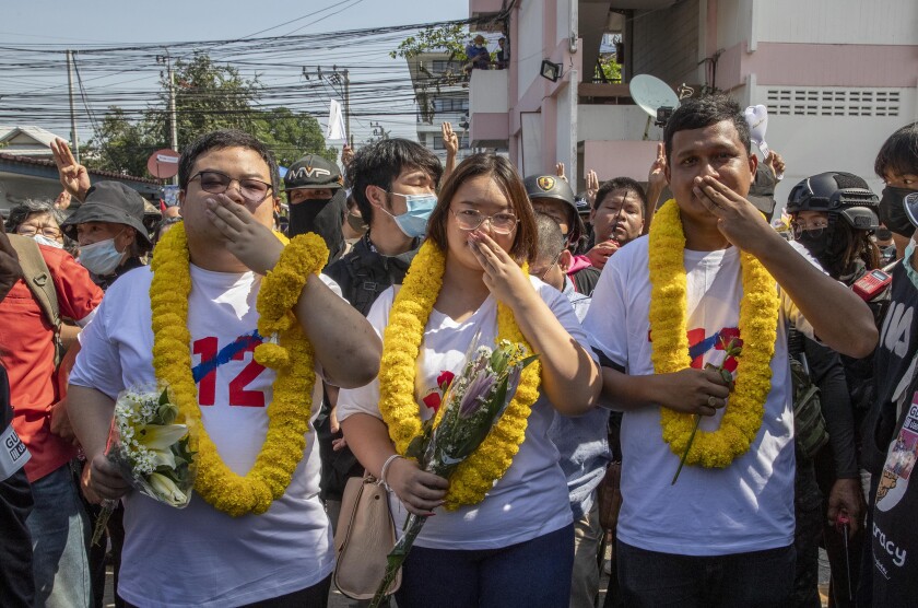Pro-democracy movement protest leaders from left, Parit Chiwarak, Panusaya Sithijirawattanakul and Shinawat Chankrajang flash three-finger salute as they walk to appear in a police station in Northaburi, Thailand, Tuesday, Dec. 8, 2020. Four leaders report to acknowledge charges that they defamed the king, the most serious of many offenses of which they stand accused during recent pro-democracy rallies. (AP Photo/Gemunu Amarasinghe)
