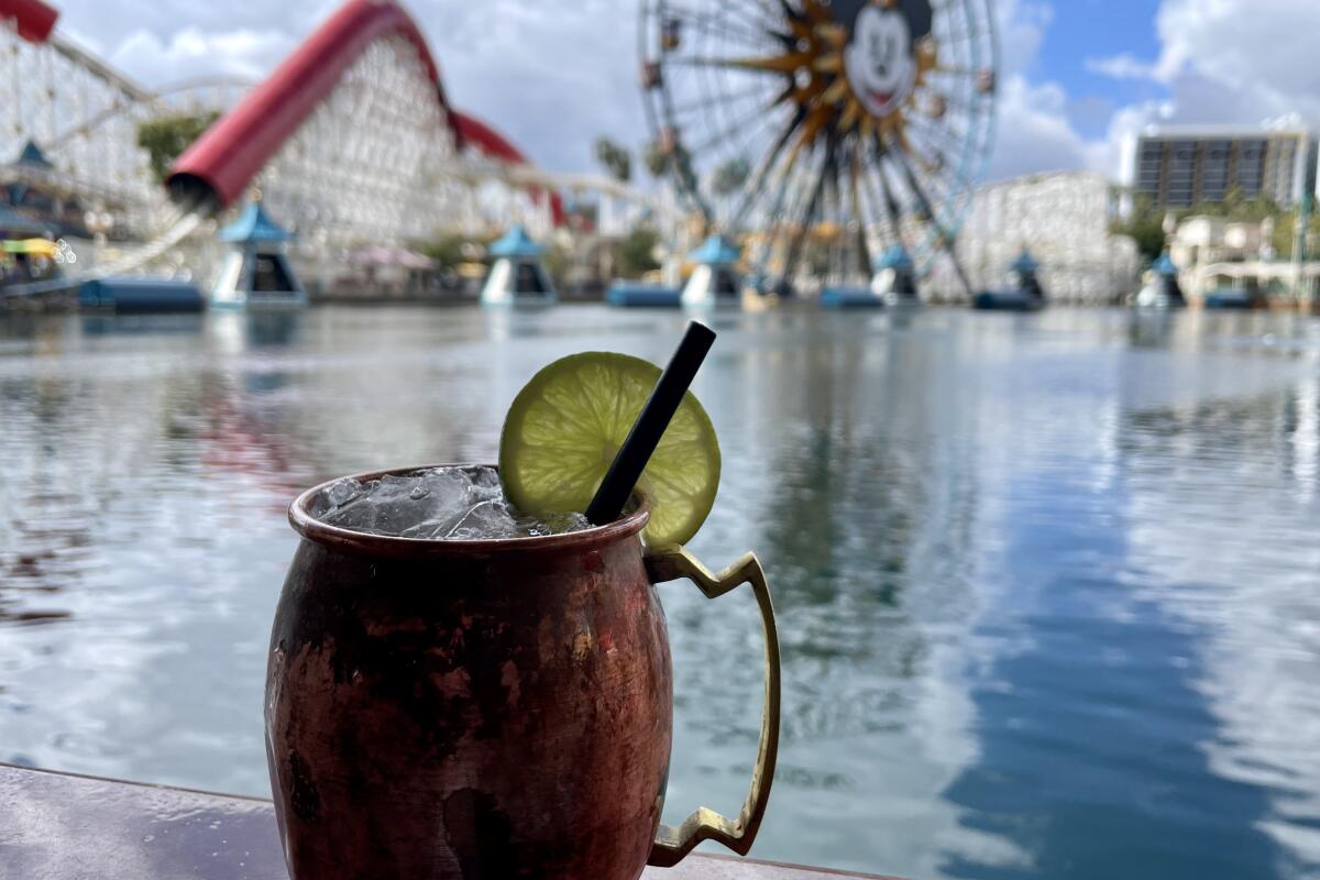 A drink with fruit garnish in a copper mug overlooks a body of water at California Adventure 