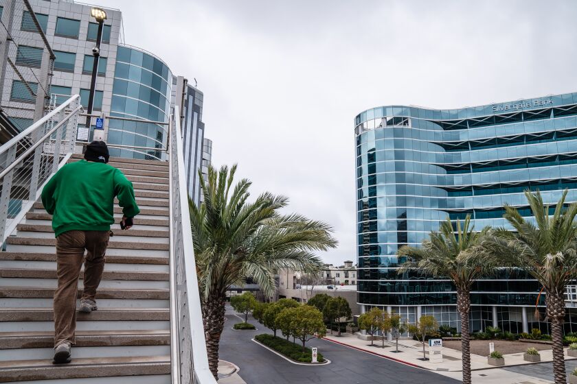 A pedestrians walks up a staircase across from the Silvergate Bank headquarters in La Jolla.
