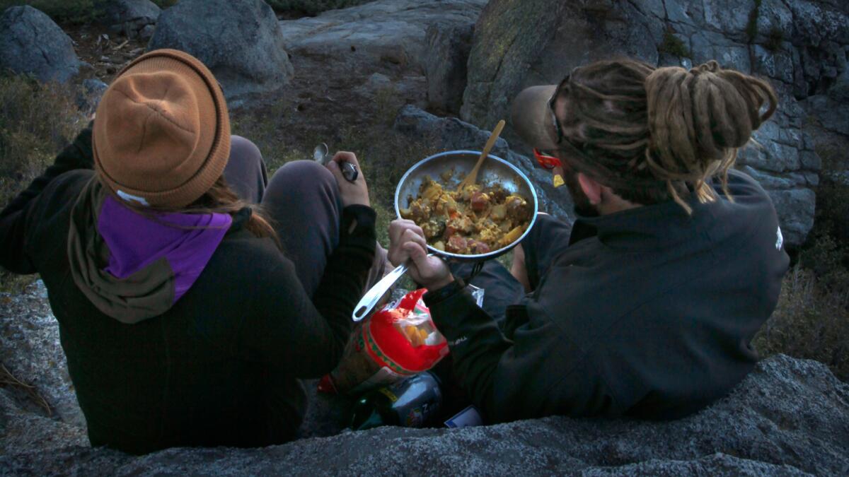 Two visitors enjoy a hot skillet of eggs, potatoes and vegetables, and a front-row seat to view Half Dome, at Washburn Point.