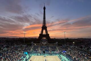 Spectators photograph a colorful sunset at Eiffel Tower Stadium prior to a beach volleyball match.