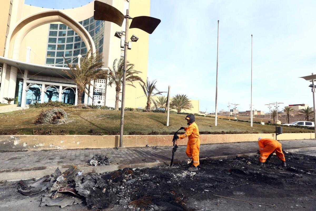 In the wake of a terrorist attack, workers clean debris from the entrance of the Corinthia Hotel in Tripoli, Libya, on Jan. 28.
