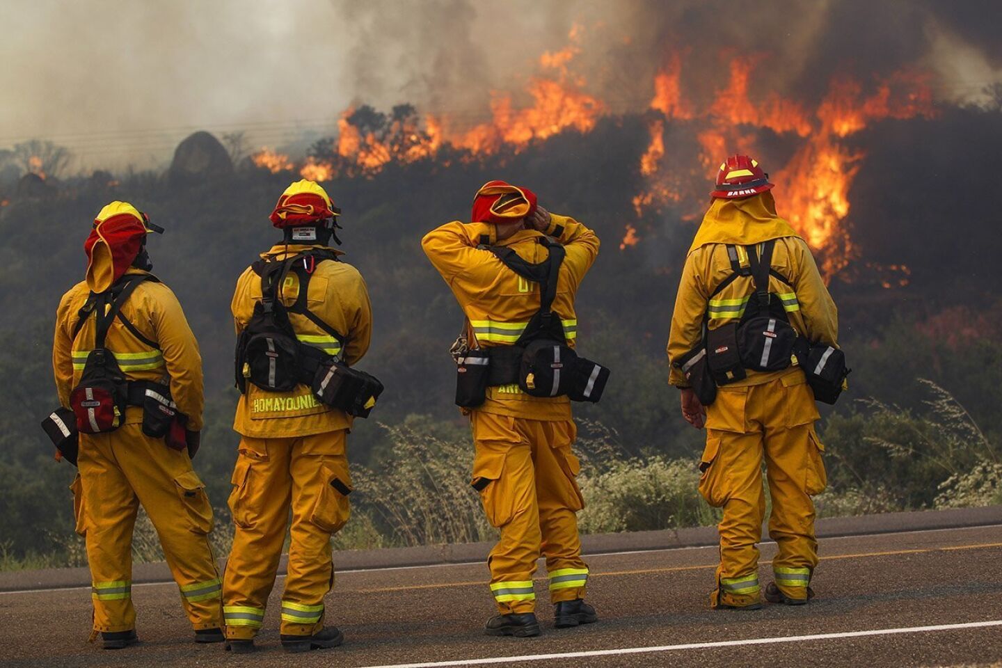 Upland firefighters, from left, Jason Alexander, Nima Homayounieh, Joseph Armendariz, and Capt. Joe Burna, watch as flames burn toward Highway 94 near Potrero on Monday.