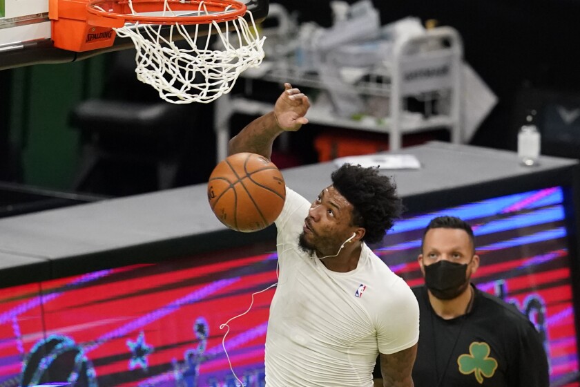 Boston Celtics' Marcus Smart dunks as he warms up before an NBA basketball game against the LA Clippers, Tuesday, March 2, 2021, in Boston. Smart has been out of action for over a month with a torn left calf muscle. While there is no exact date for Smart's anticipated return, it should be some time just after the upcoming All-Star break, according to team officials. (AP Photo/Elise Amendola)