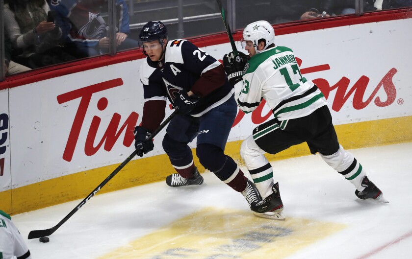 Colorado Avalanche center Nathan MacKinnon, left, looks to pass the puck as Dallas Stars center Mattias Janmark defends in the first period of an NHL hockey game Tuesday, Jan. 14, 2020, in Denver. (AP Photo/David Zalubowski)