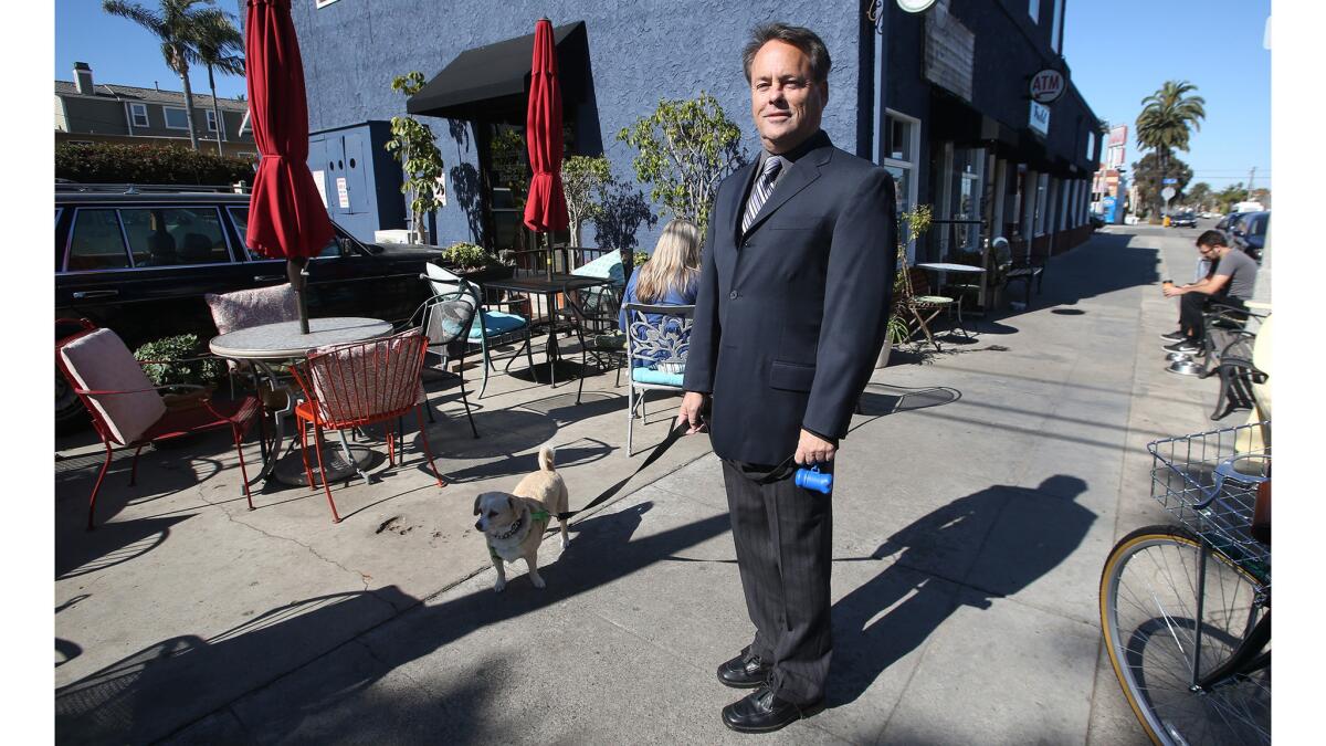 Cat detective Jack Tyler stops by what he calls his office, the Sit Stop Cafe, with his dog, Daphne, in Huntington Beach on Tuesday.