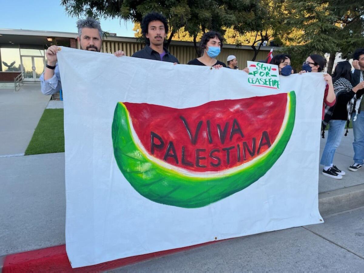 People hold a banner with a representation of a watermelon, a symbol of Palestinian unity, and the words "Viva Palestina"