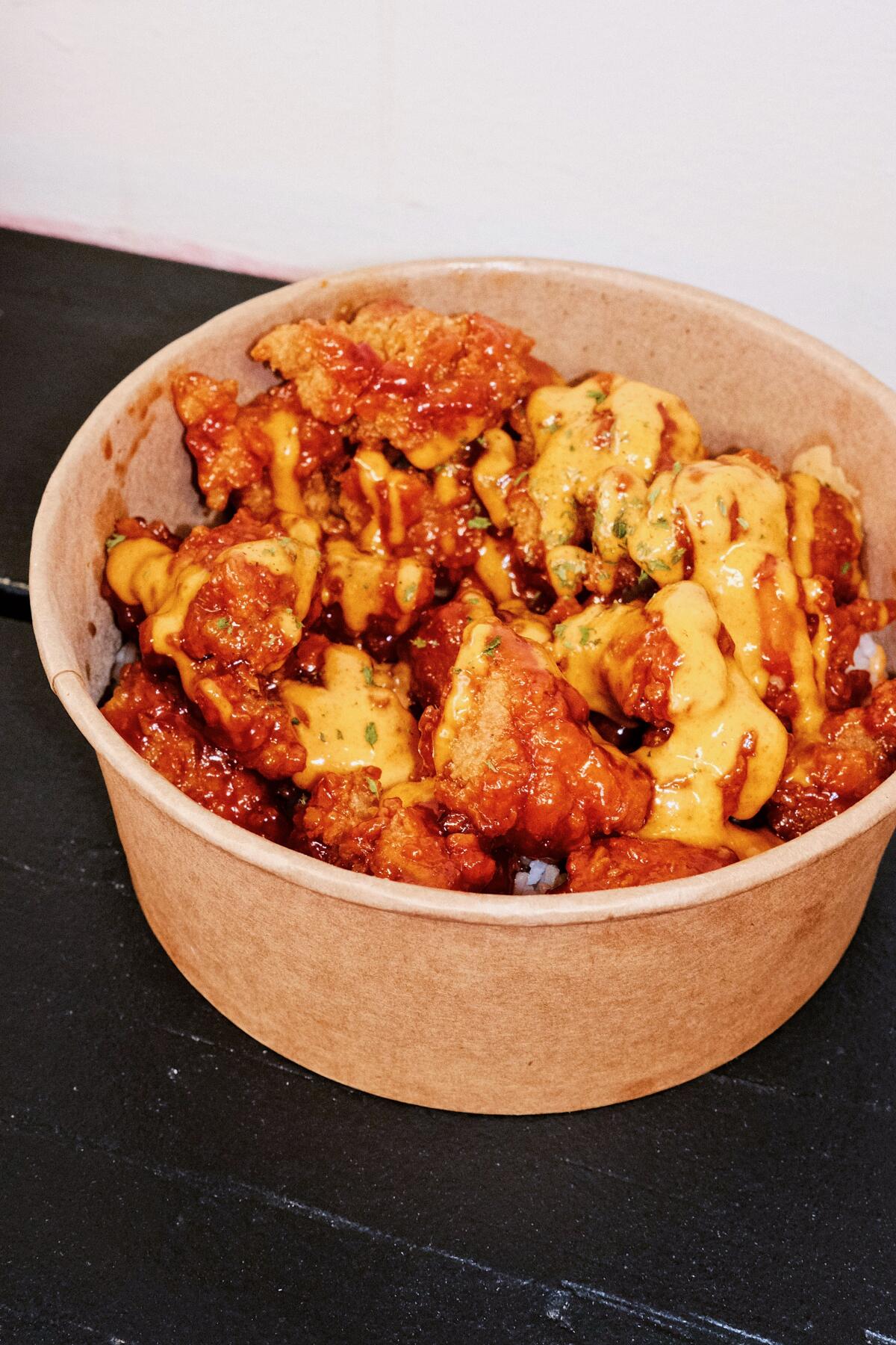 A Korean fried chicken rice bowl with sauce.