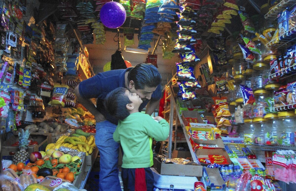Benjamin Cruz gets a kiss from his son, Jonathan, 4, while driving his produce-store truck in their Pasadena neighborhood. Cruz is one of the few vendors selling produce, snacks and household items out of a roving truck to the Latino neighborhood in Pasadena.