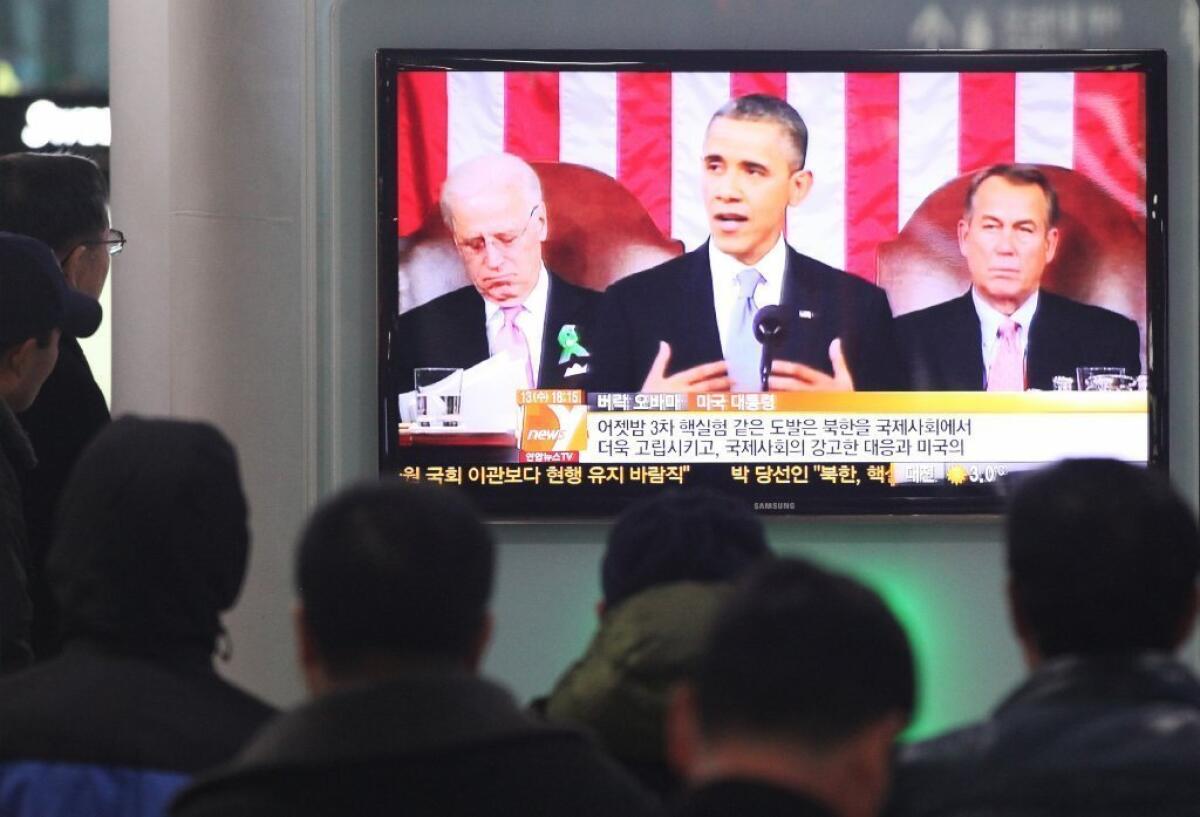 South Koreans watch a television news report on President Obama's State of the Union address at Seoul Railway Station.