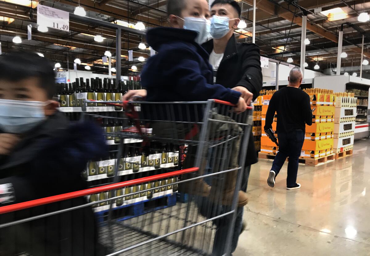 A shopper and his children wear face masks while shopping at Costco on Saturday in Alhambra, Calif.